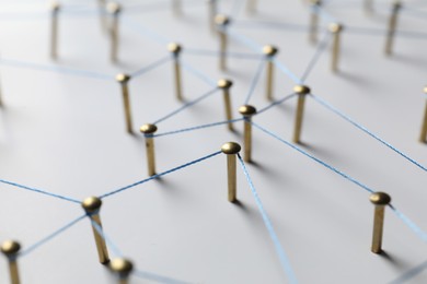 Photo of Network connection. Nails linked together by thread on white table, closeup