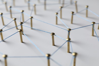 Photo of Network connection. Nails linked together by thread on white table, closeup