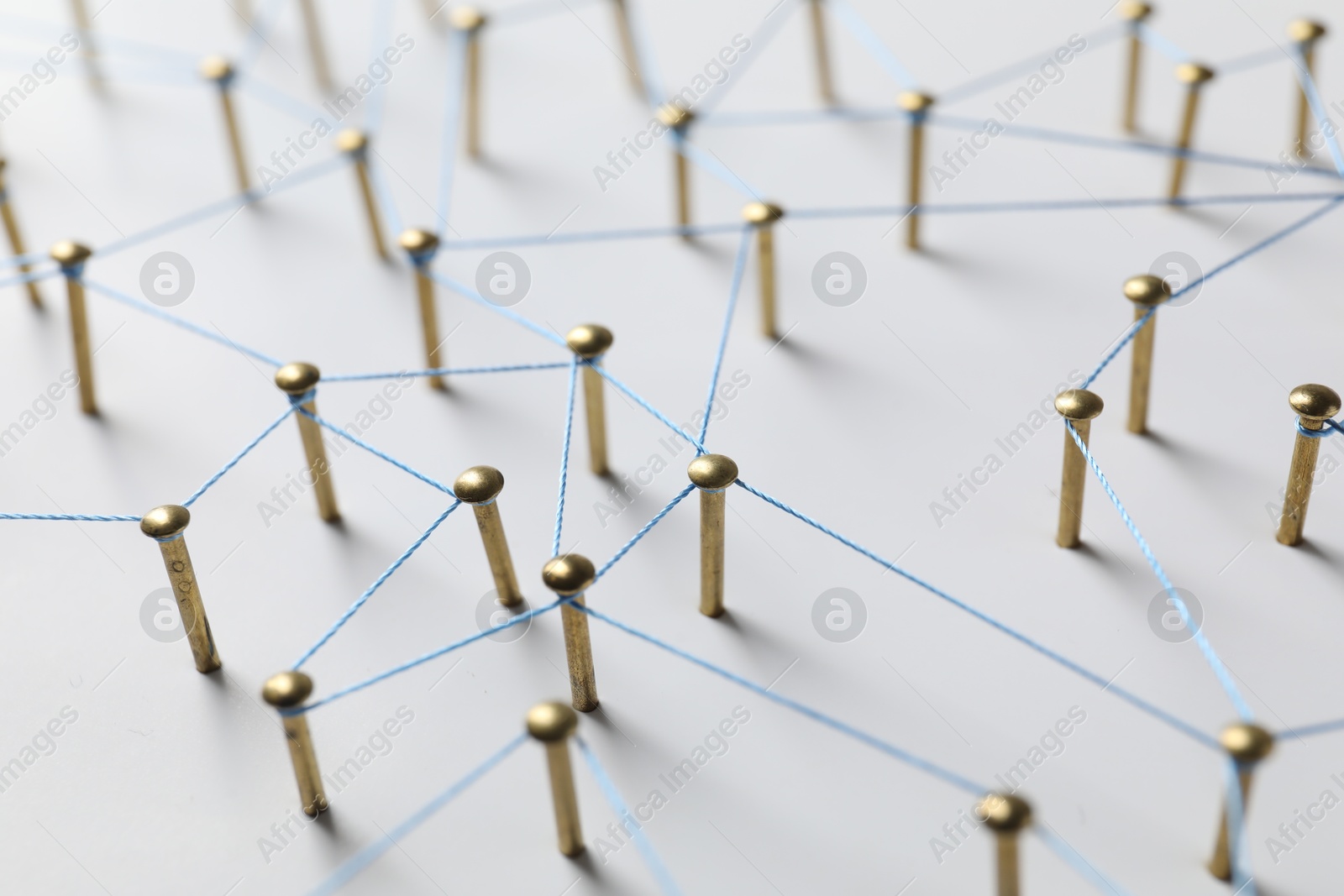 Photo of Network connection. Nails linked together by thread on white table, closeup