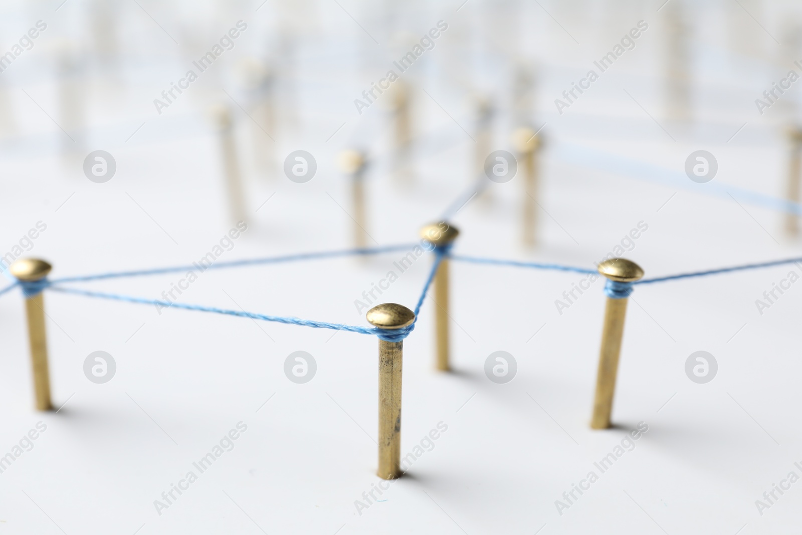 Photo of Network connection. Nails linked together by thread on white table, closeup