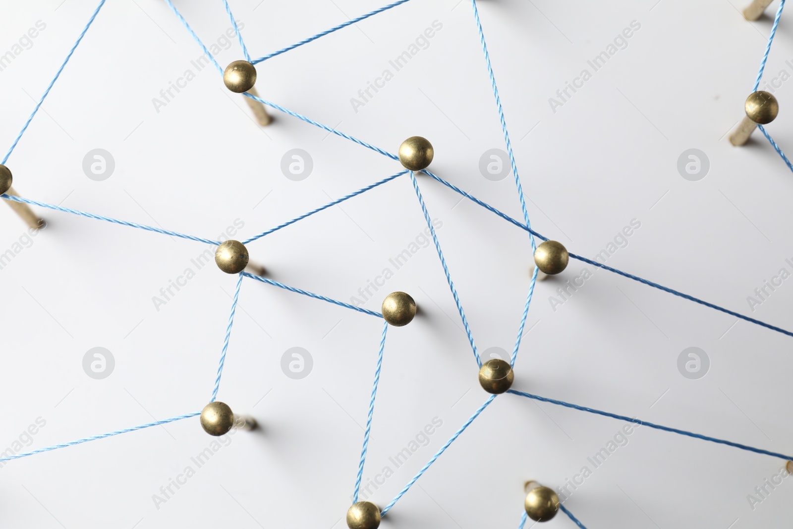 Photo of Network connection. Nails linked together by thread on white table, top view