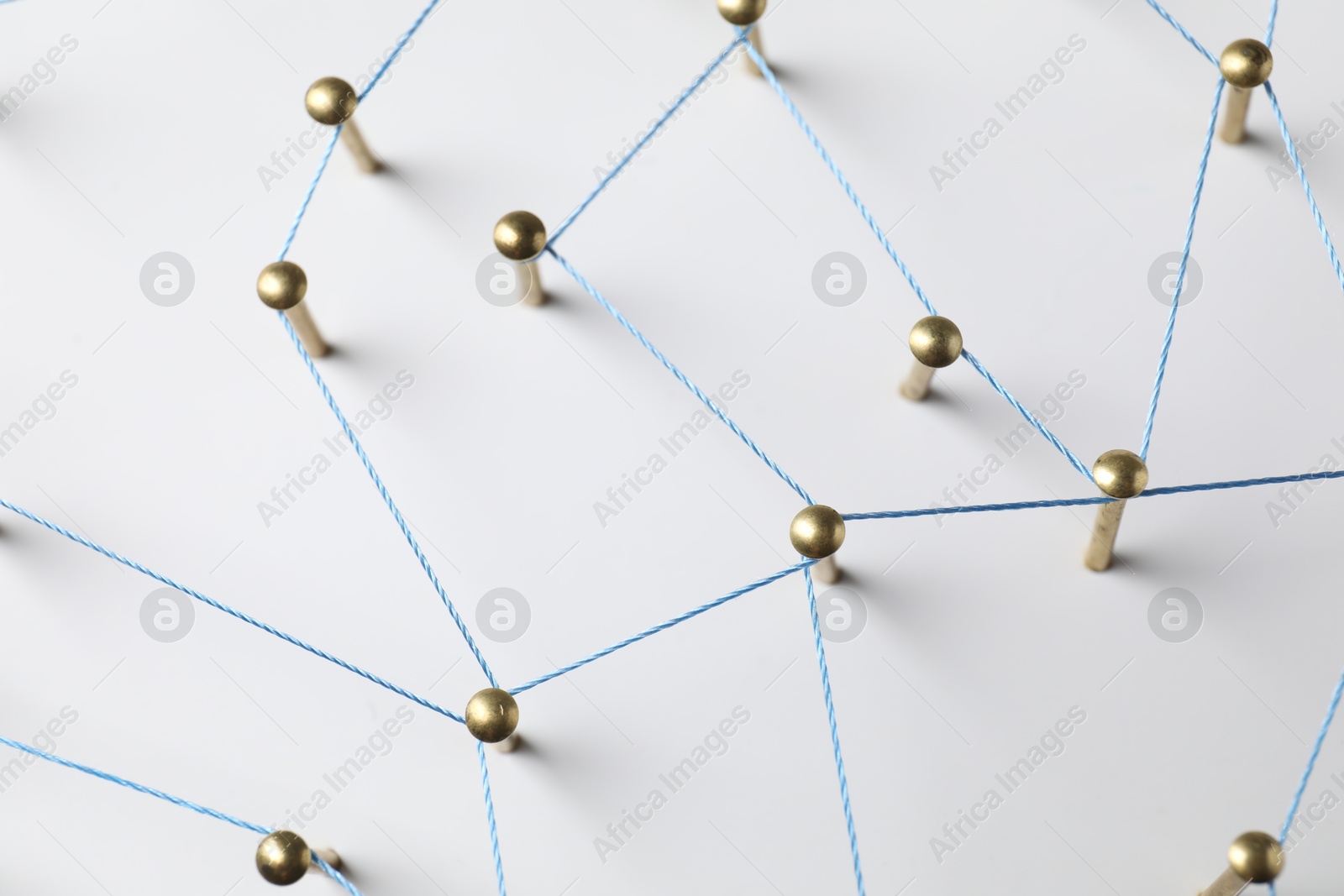 Photo of Network connection. Nails linked together by thread on white table, above view