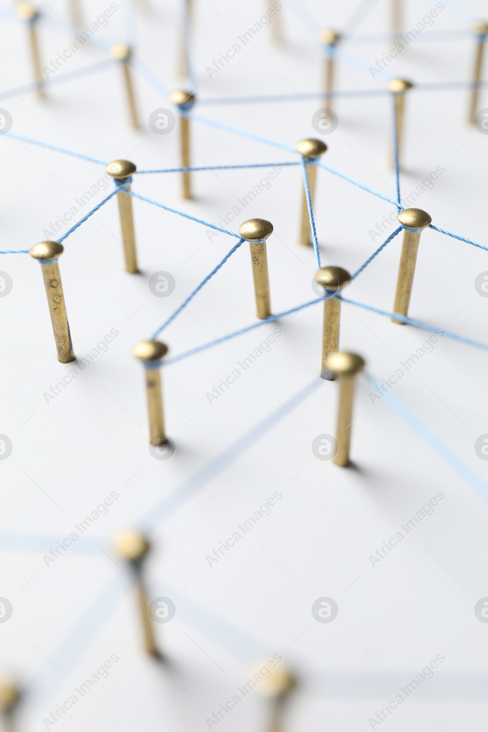 Photo of Network connection. Nails linked together by thread on white table, closeup