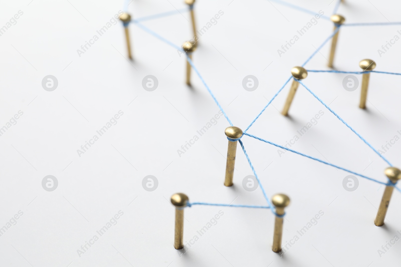 Photo of Network connection. Nails linked together by thread on white table, closeup. Space for text