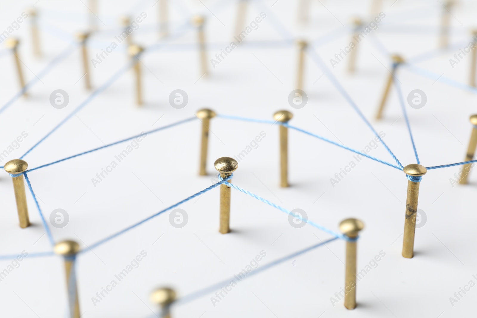 Photo of Network connection. Nails linked together by thread on white table, closeup