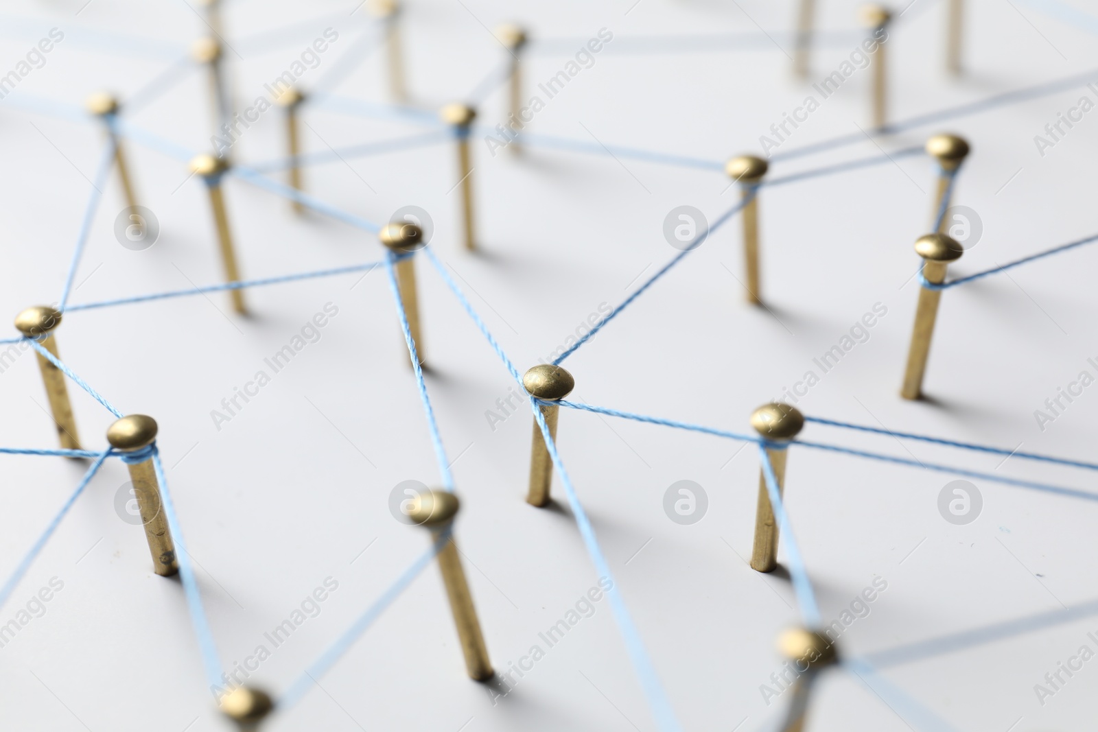 Photo of Network connection. Nails linked together by thread on white table, closeup