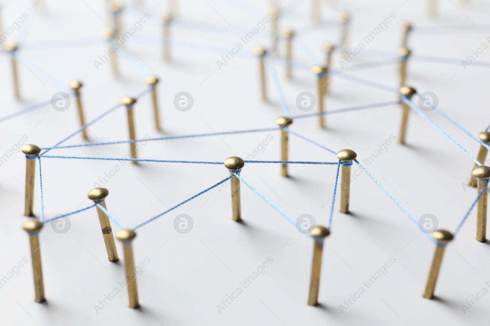 Photo of Network connection. Nails linked together by thread on white table, closeup