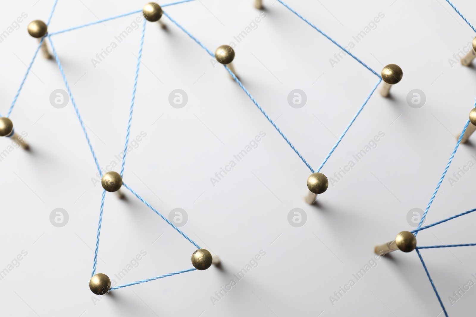 Photo of Network connection. Nails linked together by thread on white table, top view