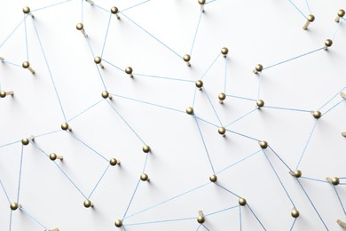 Photo of Network connection. Nails linked together by thread on white table, top view