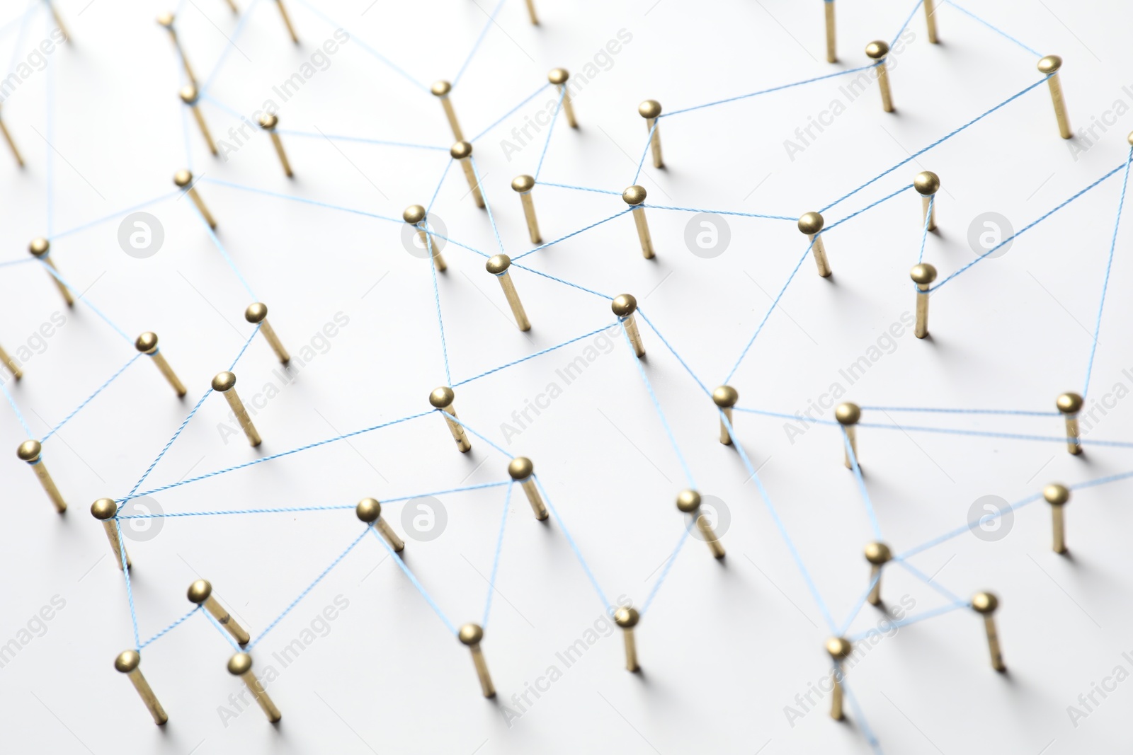 Photo of Network connection. Nails linked together by thread on white table