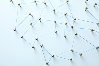 Photo of Network connection. Nails linked together by thread on white table, top view