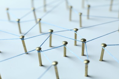 Photo of Network connection. Nails linked together by thread on white table, closeup