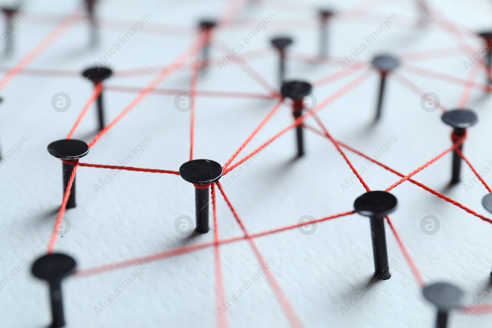 Photo of Network connection. Nails linked together by thread on white table, closeup