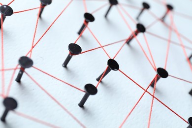 Photo of Network connection. Nails linked together by thread on white table, closeup