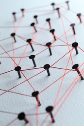 Photo of Network connection. Nails linked together by thread on white table, closeup