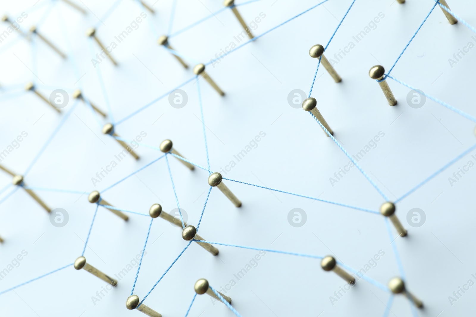 Photo of Network connection. Nails linked together by thread on white table, closeup