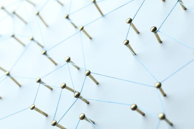 Photo of Network connection. Nails linked together by thread on white table, closeup