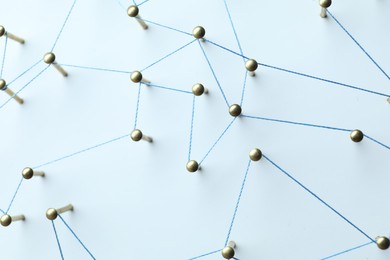 Photo of Network connection. Nails linked together by thread on white table, above view