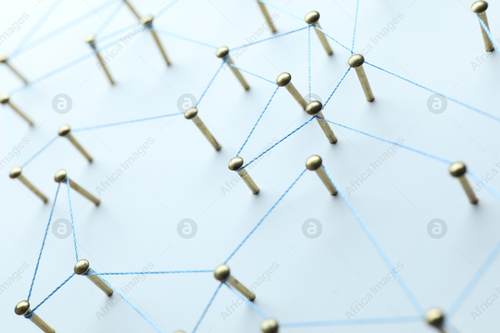 Photo of Network connection. Nails linked together by thread on white table, closeup