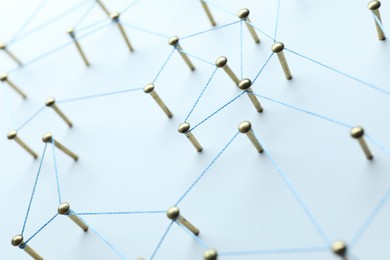 Photo of Network connection. Nails linked together by thread on white table, closeup