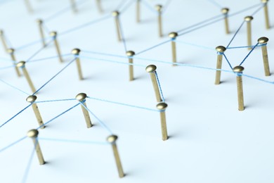 Photo of Network connection. Nails linked together by thread on white table, closeup