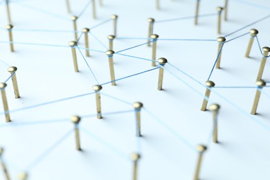 Photo of Network connection. Nails linked together by thread on white table, closeup