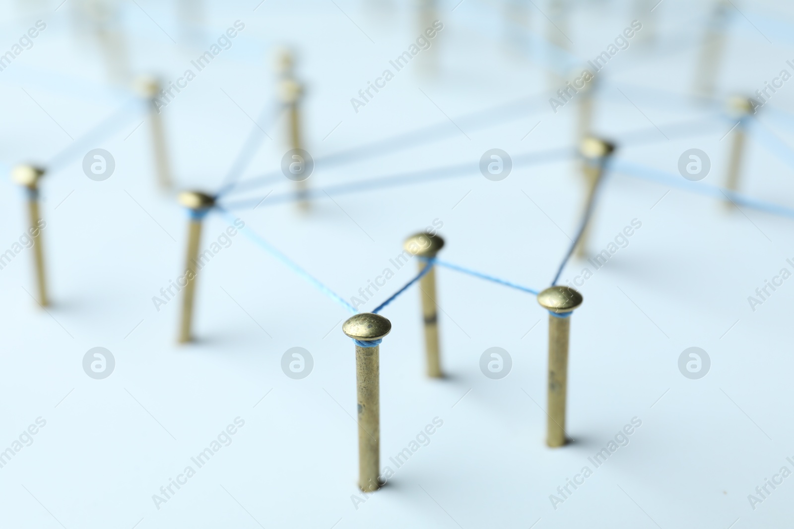 Photo of Network connection. Nails linked together by thread on white table, closeup