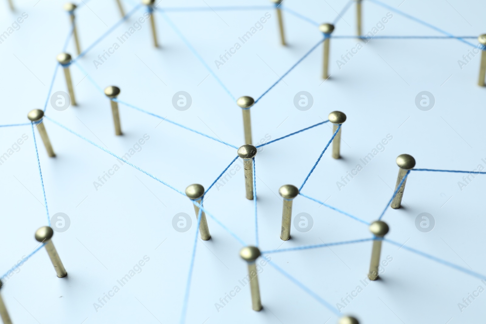 Photo of Network connection. Nails linked together by thread on white table, closeup