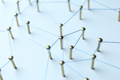 Photo of Network connection. Nails linked together by thread on white table, closeup