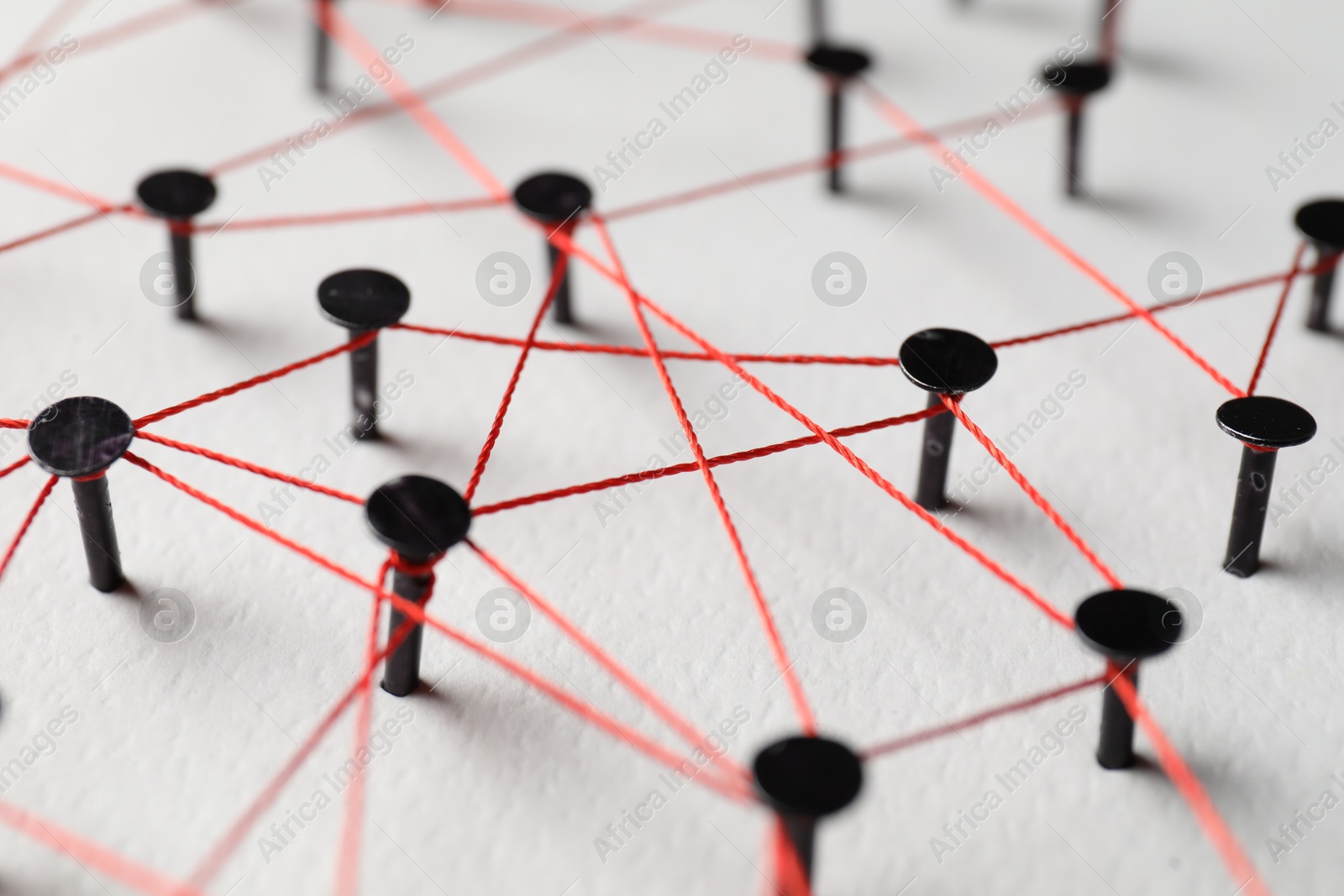 Photo of Network connection. Nails linked together by thread on white table, closeup