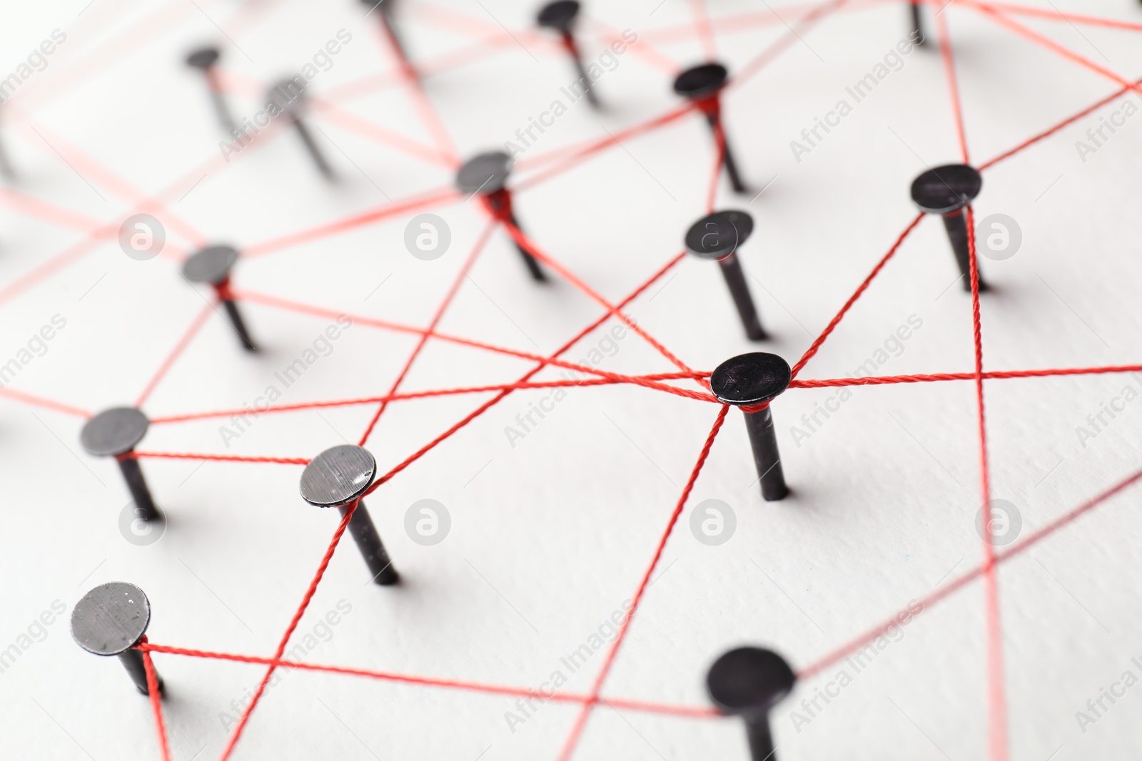 Photo of Network connection. Nails linked together by thread on white table, closeup