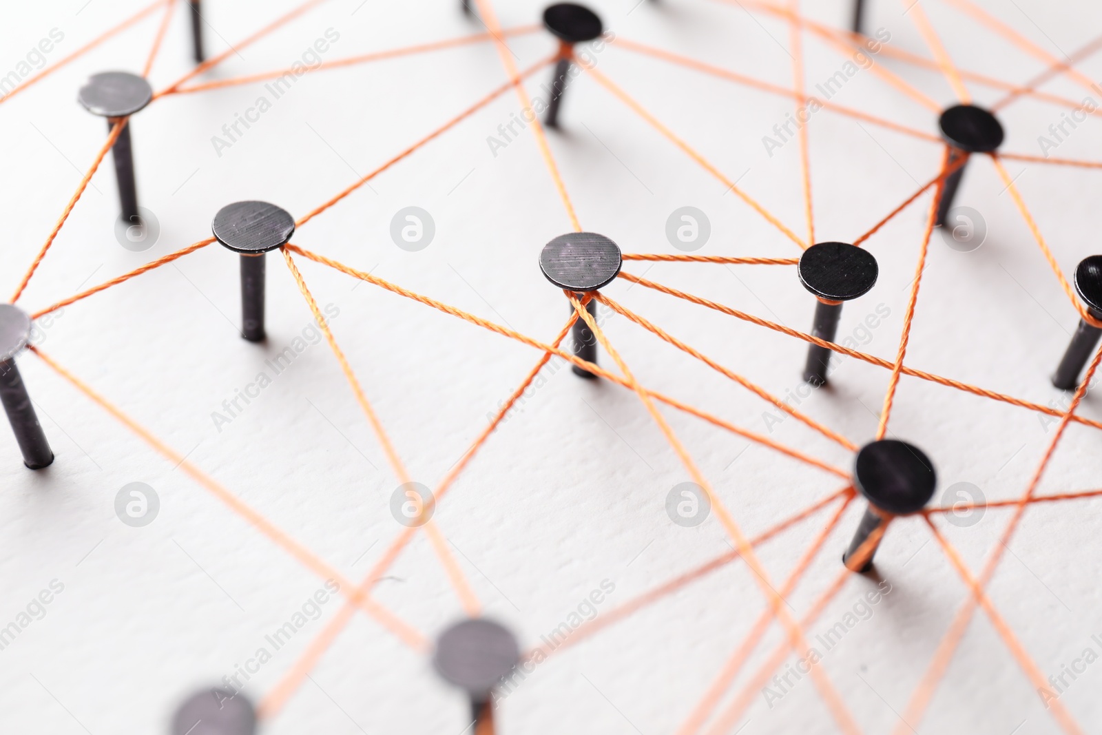 Photo of Network connection. Nails linked together by thread on white table, closeup