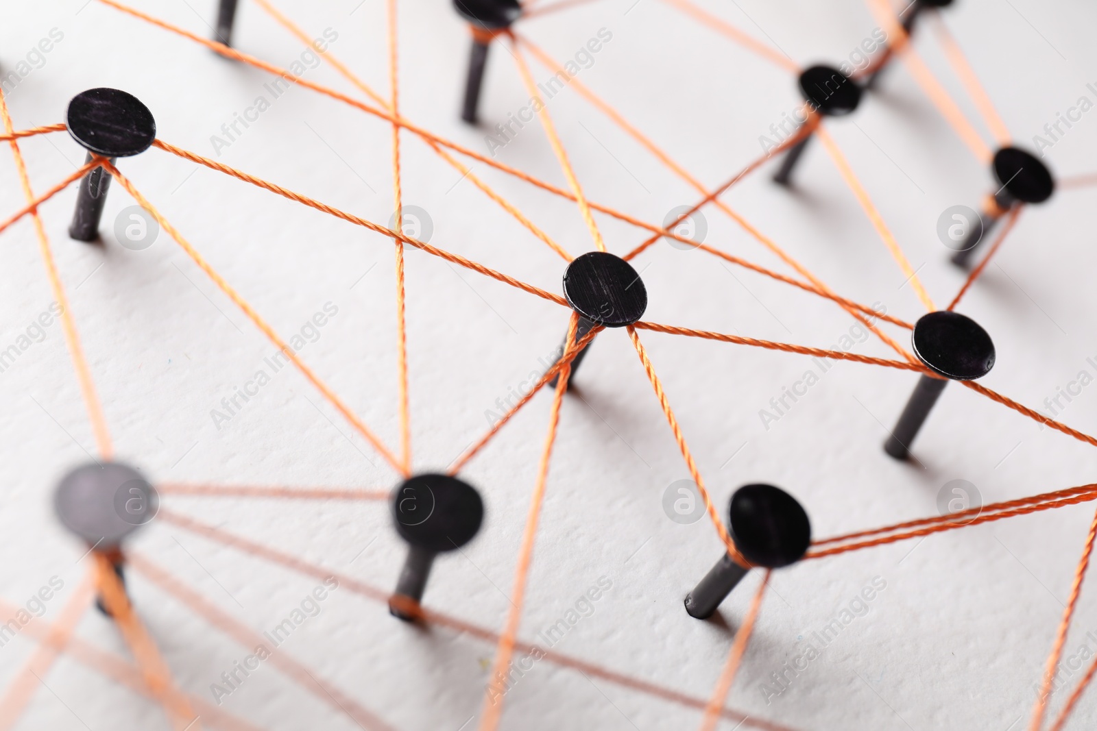 Photo of Network connection. Nails linked together by thread on white table, closeup