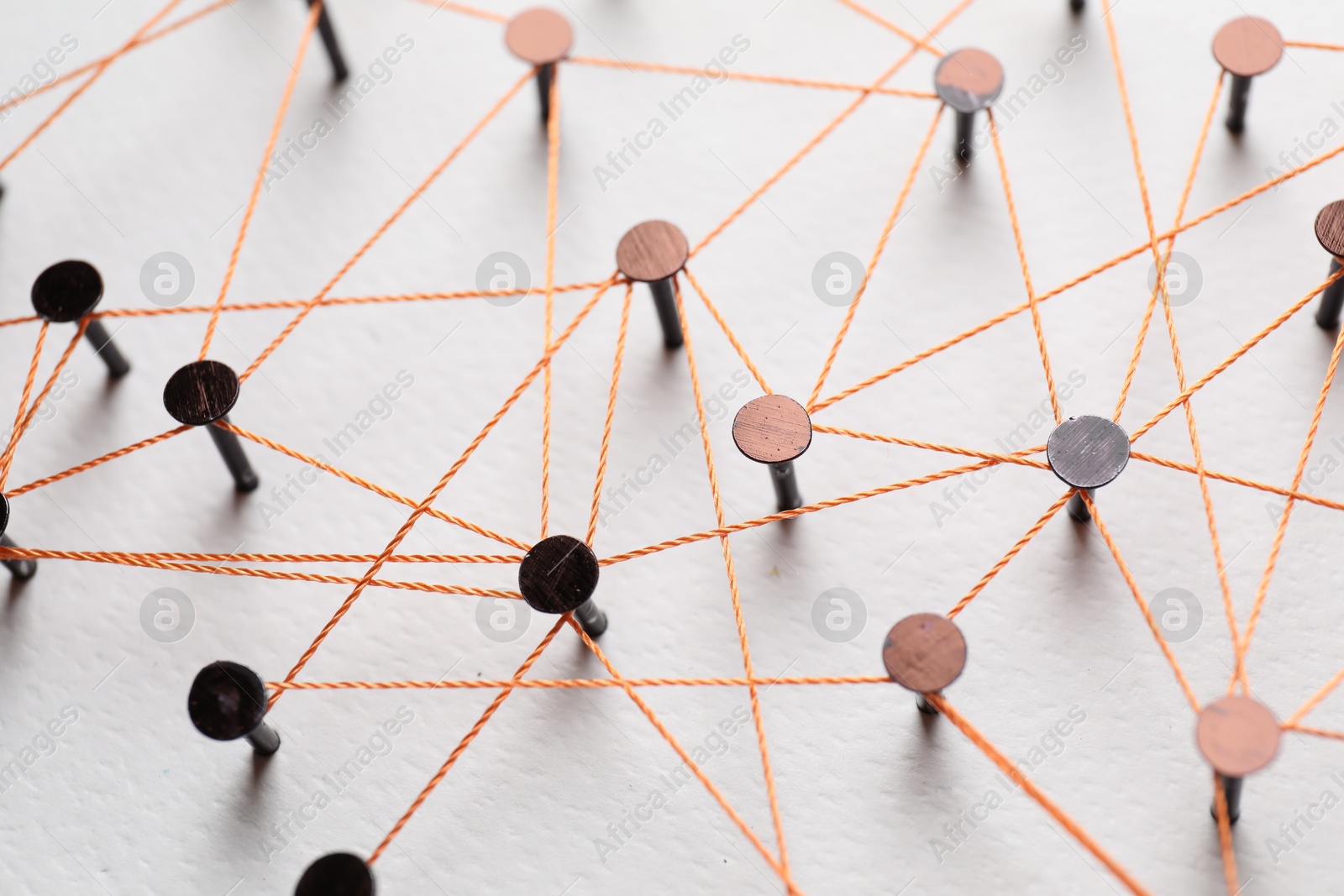 Photo of Network connection. Nails linked together by thread on white table, above view