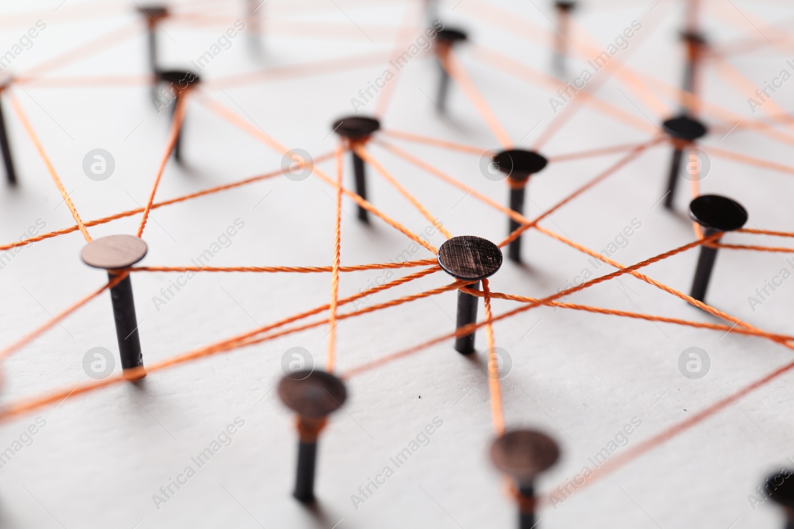 Photo of Network connection. Nails linked together by thread on white table, closeup