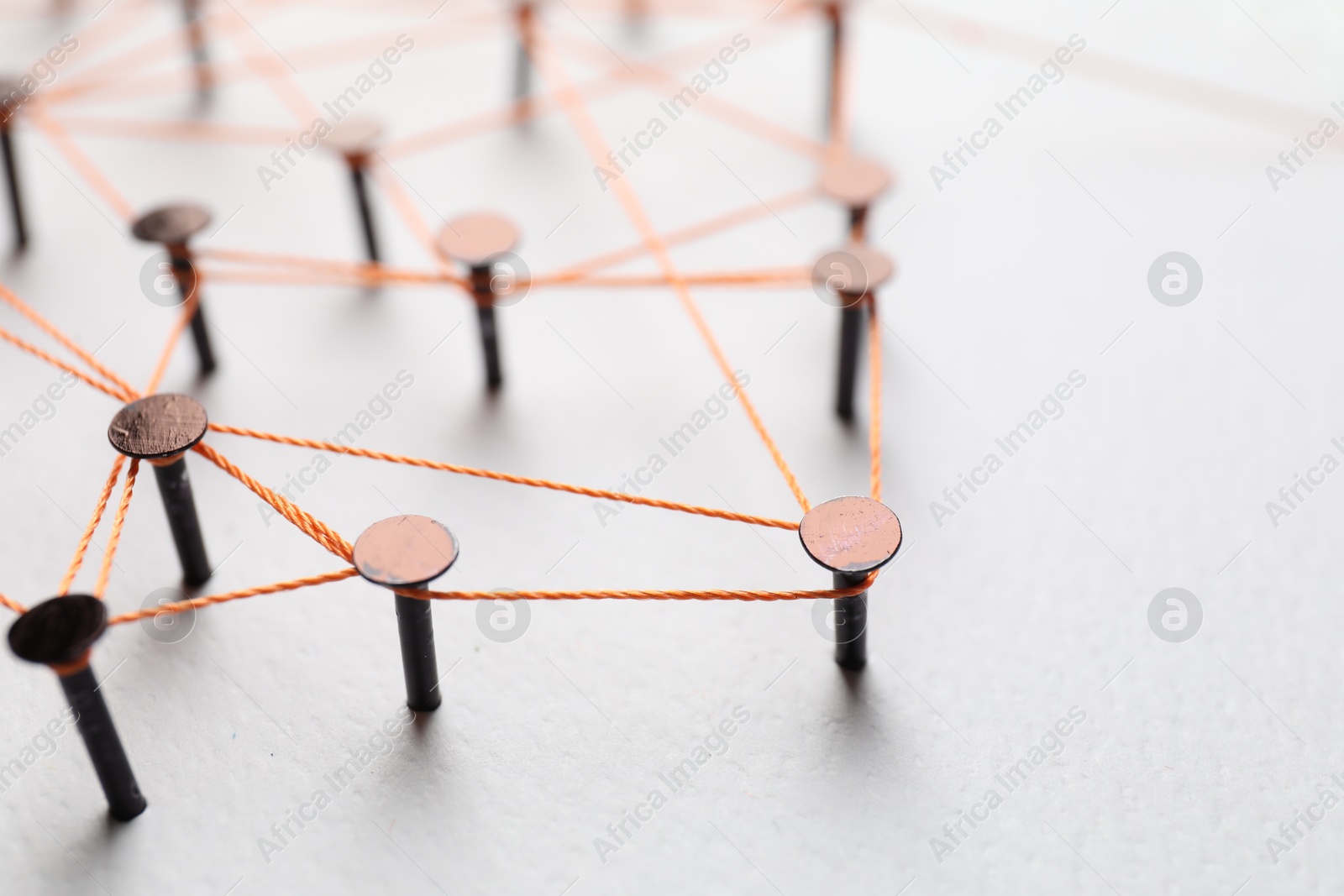 Photo of Network connection. Nails linked together by thread on white table, closeup. Space for text