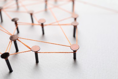 Photo of Network connection. Nails linked together by thread on white table, closeup. Space for text