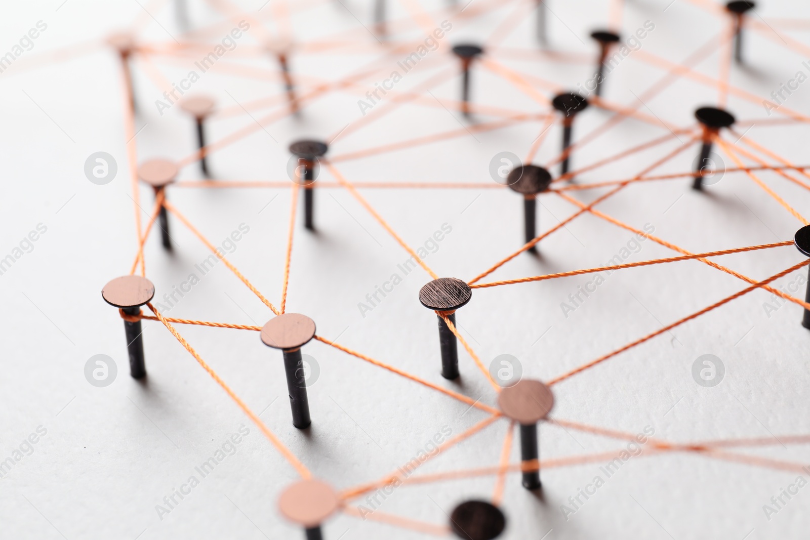 Photo of Network connection. Nails linked together by thread on white table, closeup