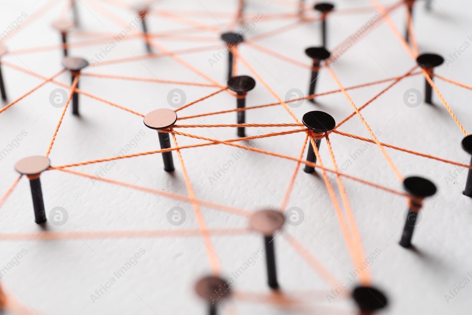 Photo of Network connection. Nails linked together by thread on white table, closeup