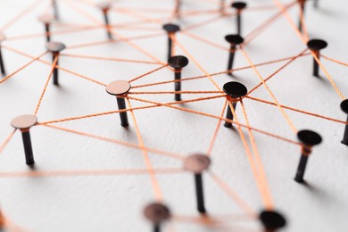 Photo of Network connection. Nails linked together by thread on white table, closeup