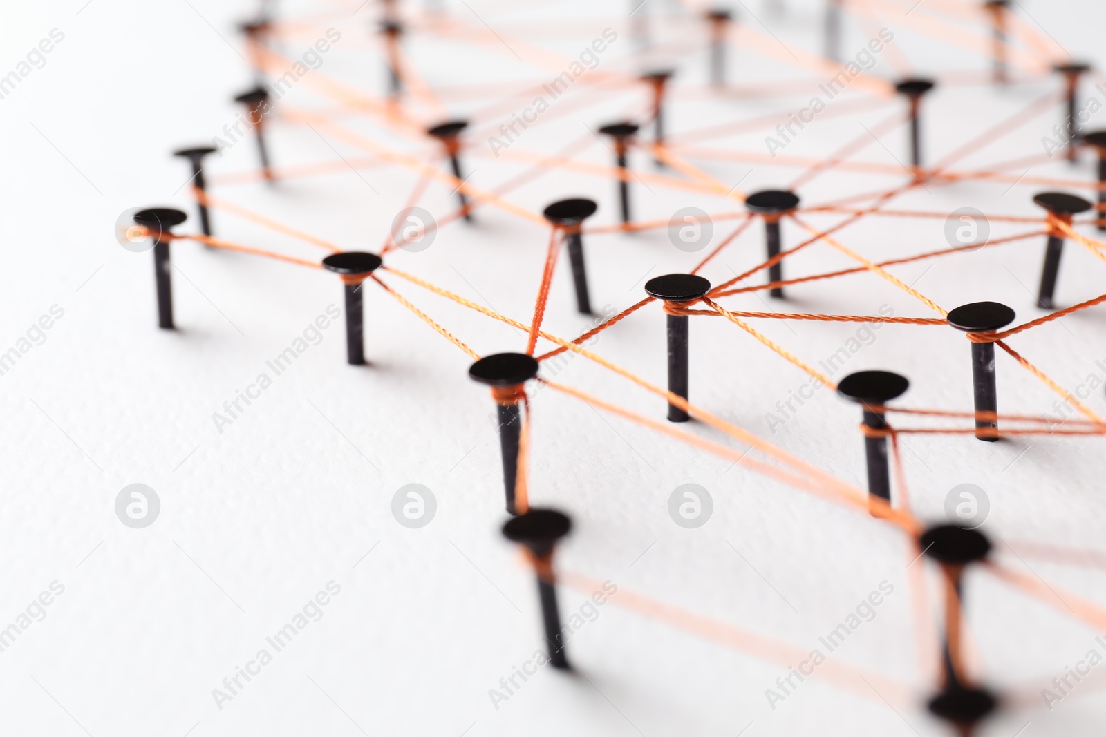 Photo of Network connection. Nails linked together by thread on white table, closeup