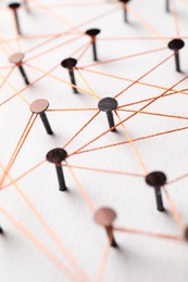 Network connection. Nails linked together by thread on white table, closeup