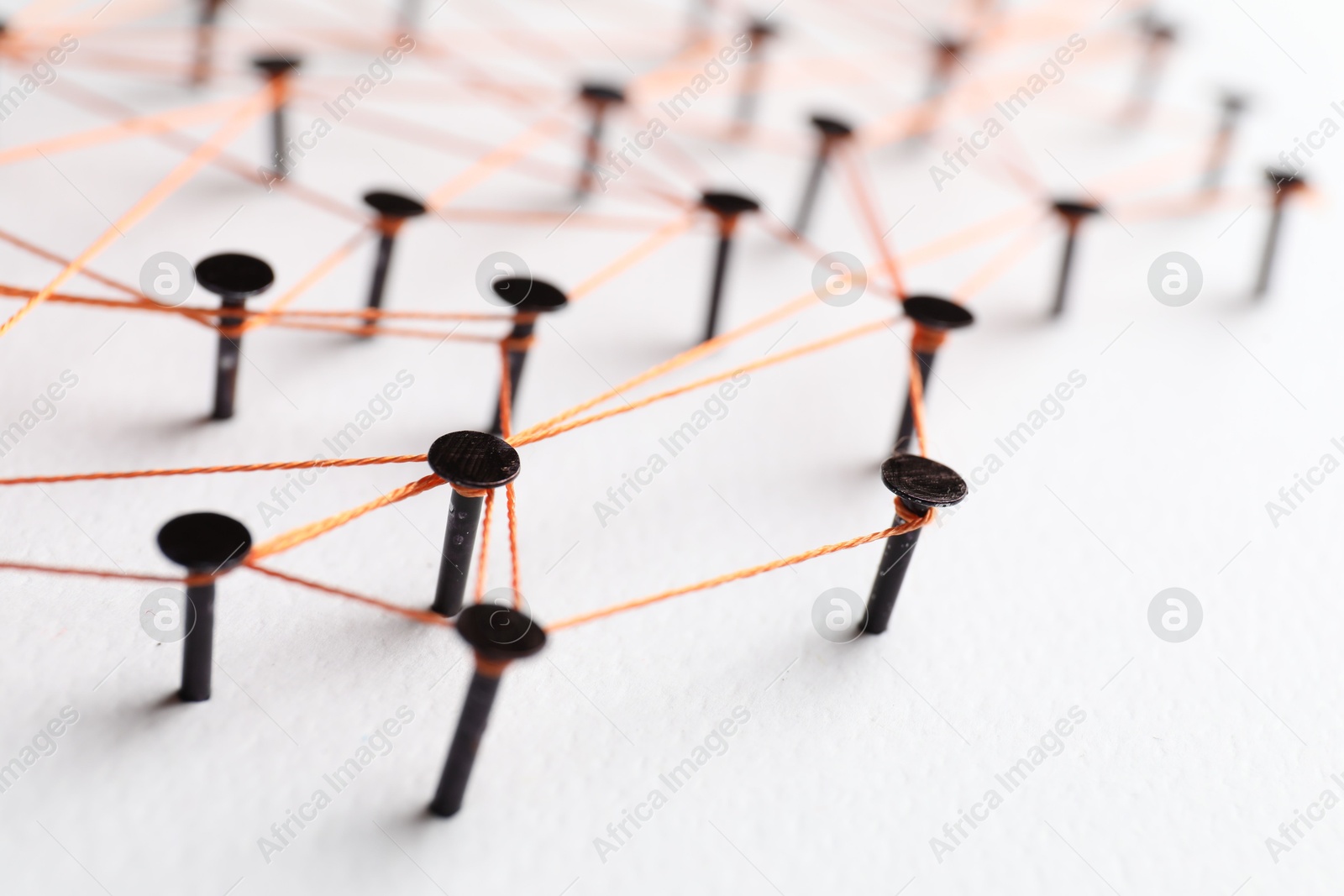 Photo of Network connection. Nails linked together by thread on white table, closeup