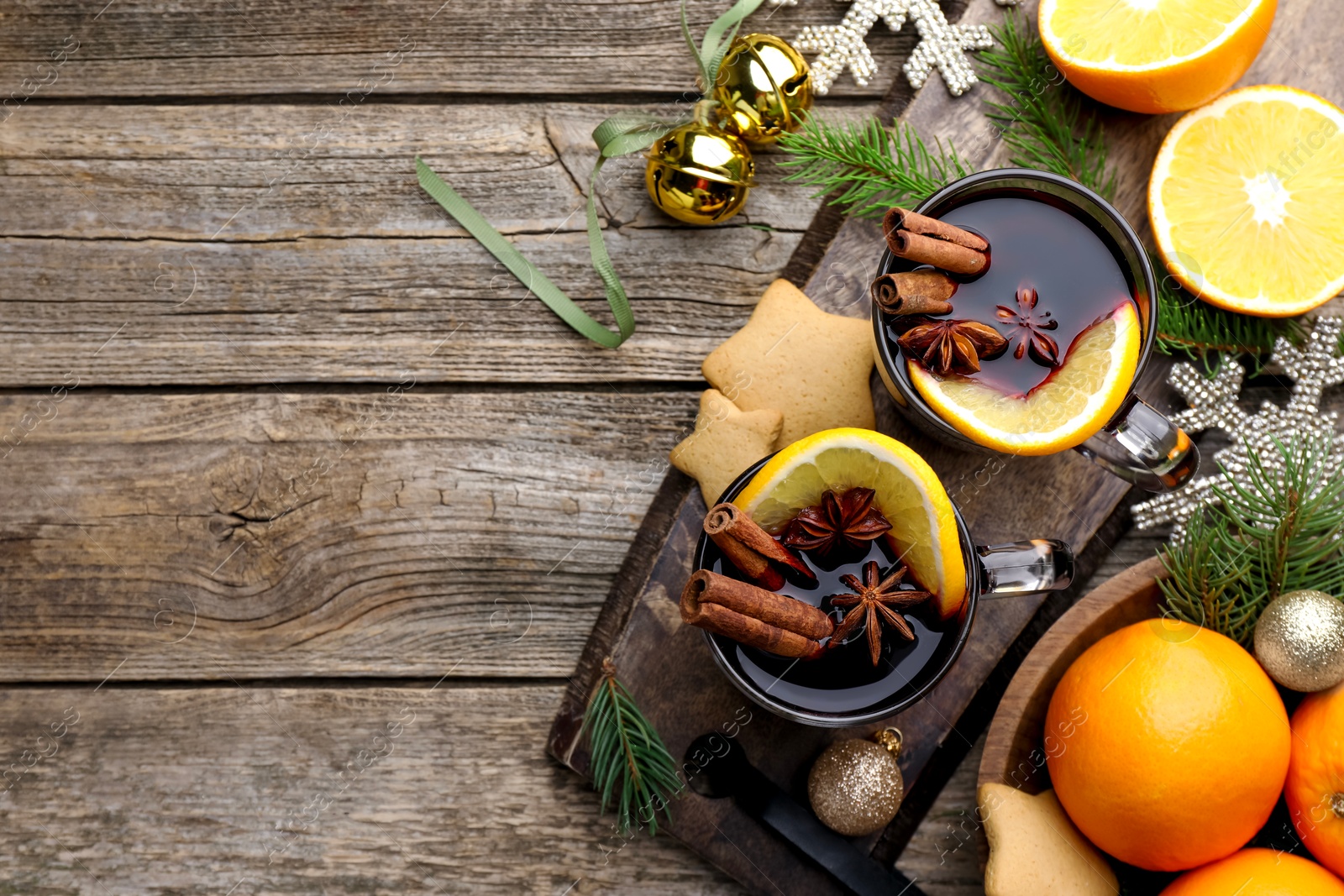 Photo of Tasty mulled wine with spices, orange, cookies and Christmas decor on wooden table, flat lay. Space for text