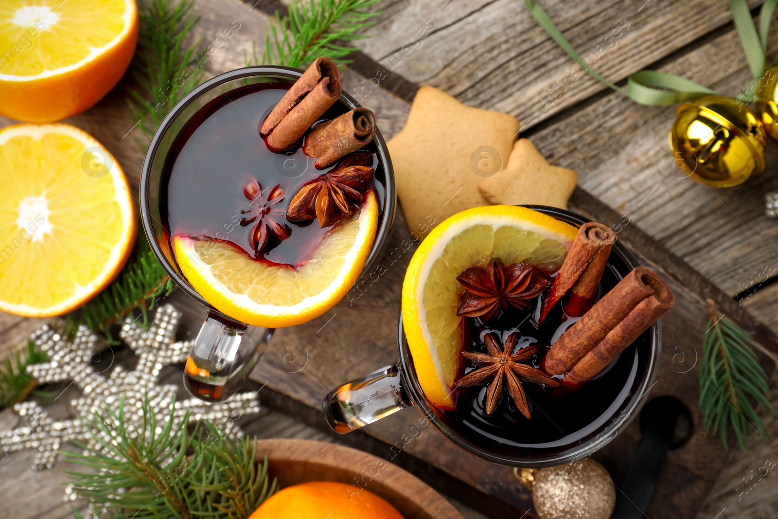 Photo of Tasty mulled wine with spices, orange slices, cookies and Christmas decor on wooden table, flat lay