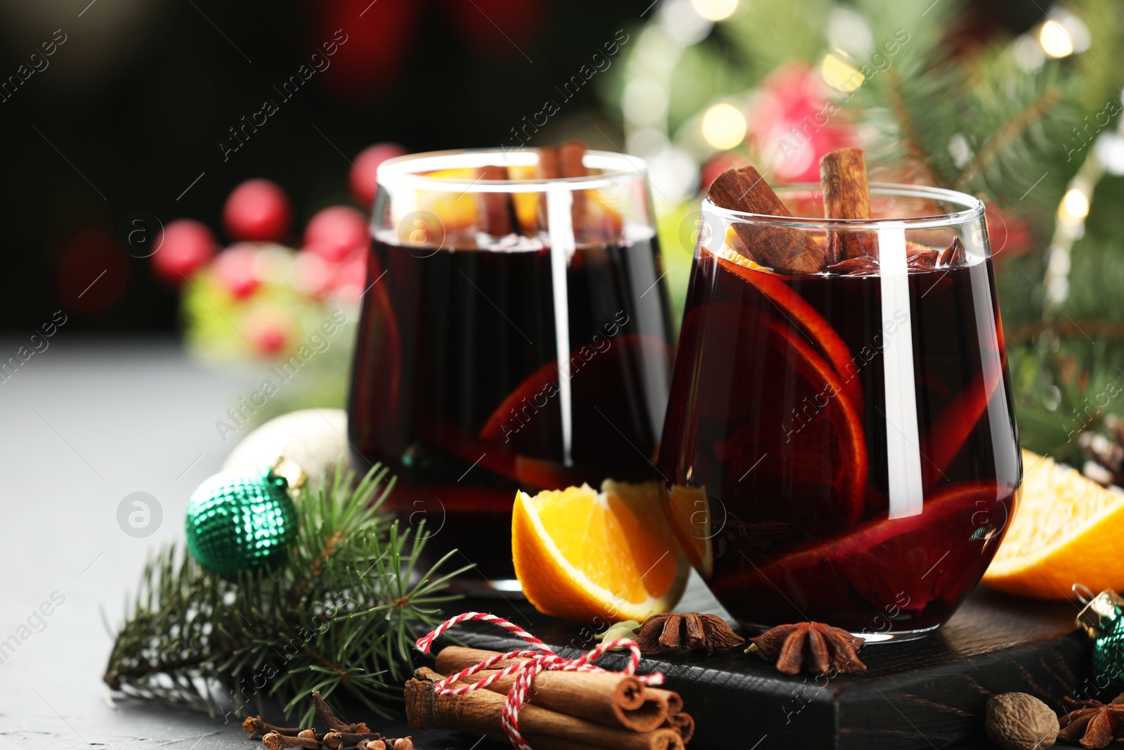 Photo of Tasty mulled wine with spices and Christmas decor on table, closeup