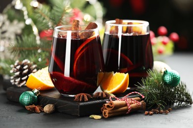 Photo of Tasty mulled wine with spices and Christmas decor on grey table