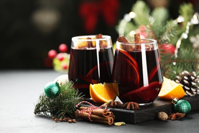 Photo of Tasty mulled wine with spices and Christmas decor on grey table, closeup