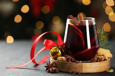 Photo of Tasty mulled wine with spices, cookies and decor on grey table against blurred Christmas lights, space for text. Bokeh effect