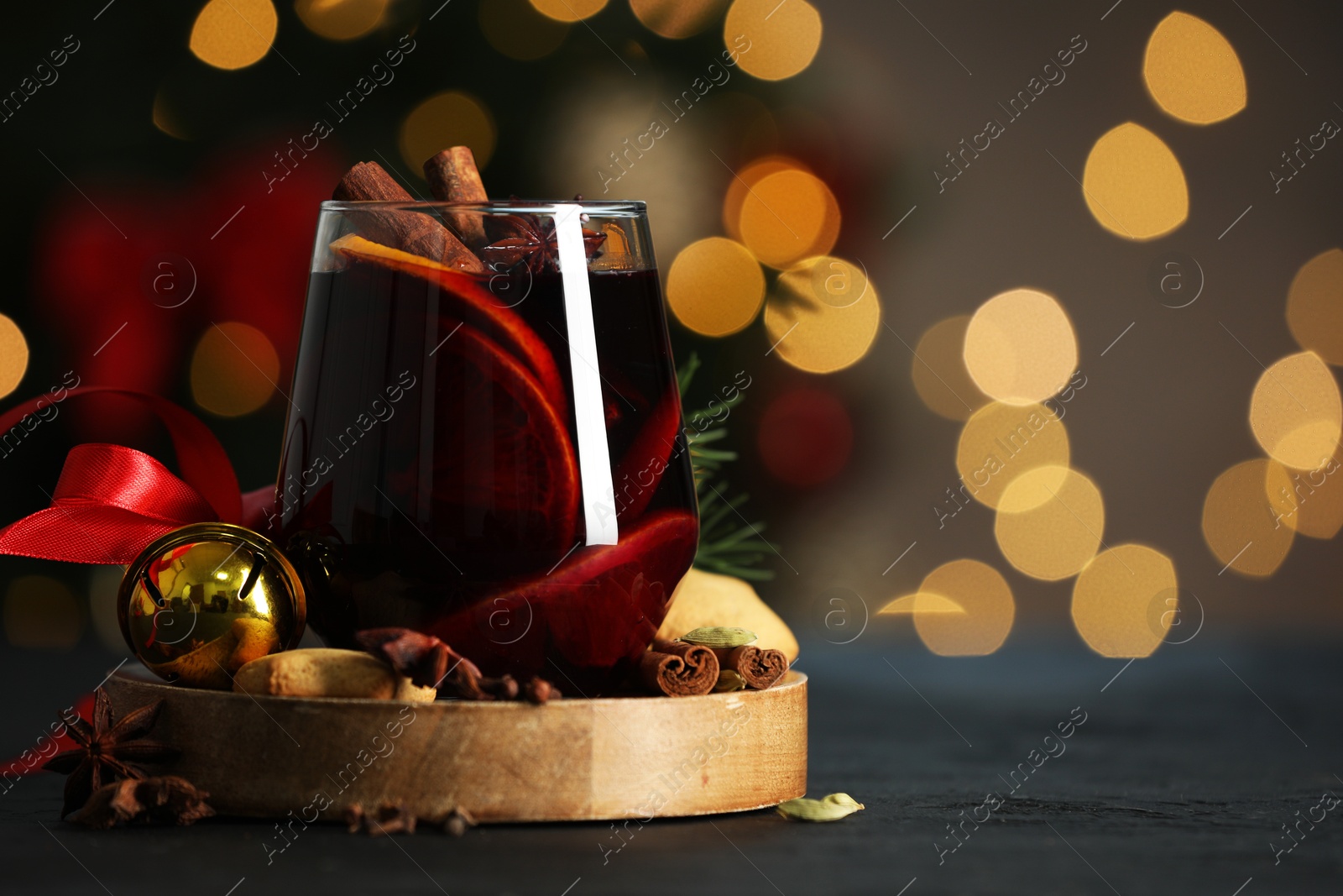 Photo of Tasty mulled wine with spices, cookies and decor on grey table against blurred Christmas lights, space for text. Bokeh effect